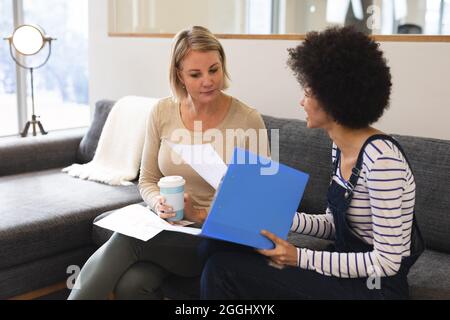 Souriant divers collègues féminins travaillant ensemble dans le salon du lieu de travail Banque D'Images