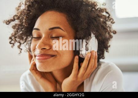 Femme souriante aux cheveux sombres, avec casque sans fil Banque D'Images