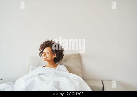 Joyeuse femme afro-américaine couchée au lit Banque D'Images