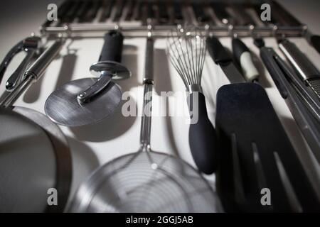 Ensemble d'outils de cuisine organisés suspendus au mur de la cuisine de la maison Banque D'Images