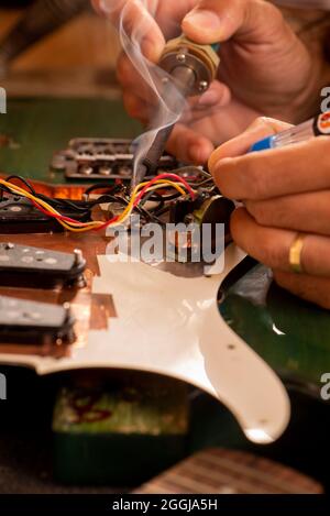 les mains de l'homme soudant un fil de guitare électrique dans son atelier Banque D'Images