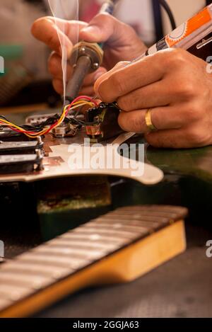 les mains de l'homme soudant un fil de guitare électrique dans son atelier Banque D'Images