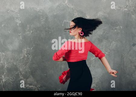 Jeune femme espagnole adulte dansant le flamenco dans un studio vintage gris arrière-plan Banque D'Images