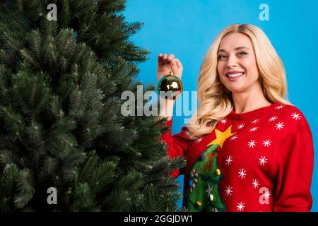 Photo de jeune positive heureuse blonde femme tenir le ballon décorer arbre Noël isolé sur fond bleu pastel Banque D'Images