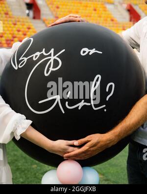 Jeune couple méconnaissable tient un ballon gonflable avec l'inscription fille ou garçon. Douche de bébé Banque D'Images