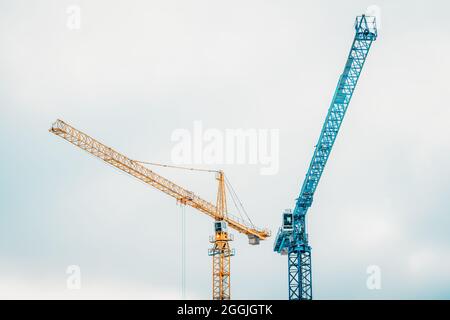 Belles grues de type tour bleu et jaune à marteler coloré sur le fond d'un ciel nuageux Banque D'Images