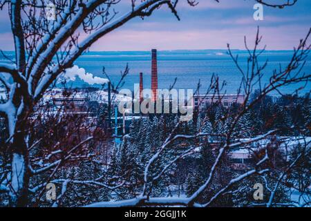 Une belle vue colorée depuis la côte à falaise (côte d'abrasion) sur la colonie de Haanneeme et une usine avec des cheminées imposantes pendant un coucher de soleil froid d'hiver Banque D'Images