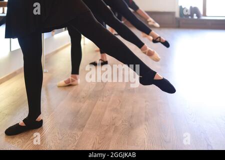 La partie basse des jambes élégantes des danseurs de ballet debout dans une rangée effectuer des exercices d'étirement Banque D'Images