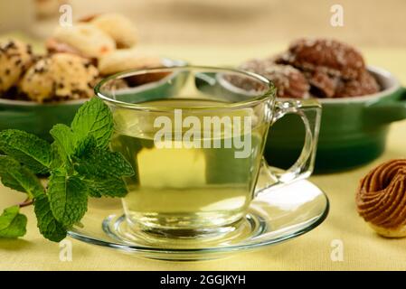thé à la menthe dans une tasse transparente avec des biscuits sucrés autour Banque D'Images