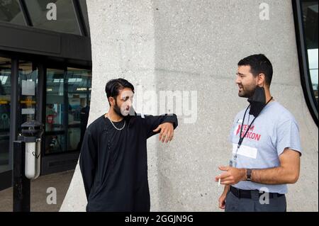 Mohammad Jelani, à gauche, un hélicoptère mécanicien de la base aérienne de Bagram qui a été évacué d'Afghanistan, partage une cigarette avec un accompagnateur après son arrivée à l'aéroport international de Washington-Dulles, à Chantilly, en Virginie, le mercredi 1er septembre, 2021. Crédit : Rod Lamkey/CNP/MediaPunch Banque D'Images