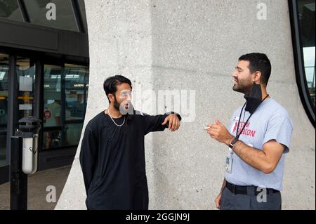 Mohammad Jelani, à gauche, un hélicoptère mécanicien de la base aérienne de Bagram qui a été évacué d'Afghanistan, partage une cigarette avec un accompagnateur après son arrivée à l'aéroport international de Washington-Dulles, à Chantilly, en Virginie, le mercredi 1er septembre, 2021. Crédit : Rod Lamkey/CNP/MediaPunch Banque D'Images