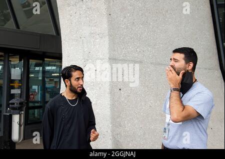 Mohammad Jelani, à gauche, un hélicoptère mécanicien de la base aérienne de Bagram qui a été évacué d'Afghanistan, partage une cigarette avec un accompagnateur après son arrivée à l'aéroport international de Washington-Dulles, à Chantilly, en Virginie, le mercredi 1er septembre, 2021. Crédit : Rod Lamkey/CNP/MediaPunch Banque D'Images