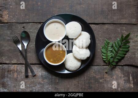 Collations sud-indiennes idli sambar ou sambhar de façon piquante préparé par le riz fermenté à la vapeur et servi avec une trempette à la noix de coco et une soupe de légumes. Banque D'Images