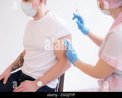 Vaccination Covid-19. Homme de race blanche se faire vacciner contre le coronavirus recevant le vaccin Covid injection intramusculaire pendant l'AP du médecin Banque D'Images