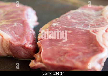 un steak cru sur une planche de bois Banque D'Images