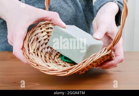 Fleuriste au travail: Comment faire l'arrangement floral d'automne dans le panier en osier utilisant des fleurs séchées et d'autres plantes. Étape par étape, tutoriel. Banque D'Images