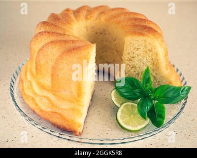 baba au rhum sur l'assiette en verre avec du citron vert et du basilic. Gâteau de levure rond fait maison. Dessert italien Banque D'Images