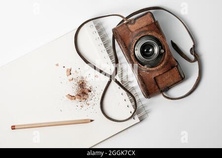 Carnet avec crayon marron et ancien appareil photo sur fond blanc Banque D'Images