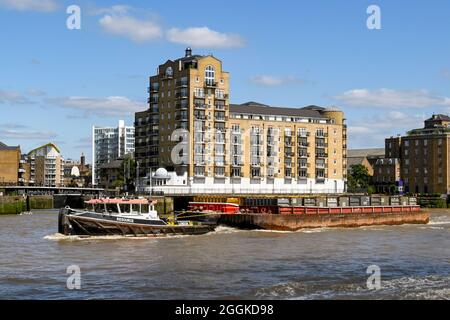 Londres, Angleterre - août 2021 : remorqueurs industriels remorquant une grande barge avec des conteneurs sur la Tamise. Banque D'Images