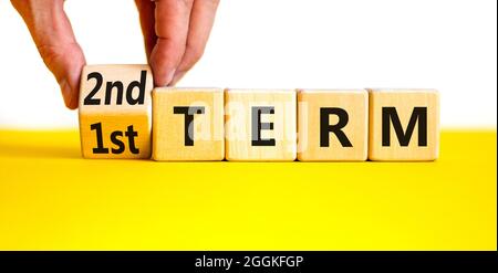 Symbole du premier ou du deuxième terme. Homme d'affaires transforme un cube et change les mots '1er terme' en '2e terme'. Belle table jaune, fond blanc. Affaires a Banque D'Images