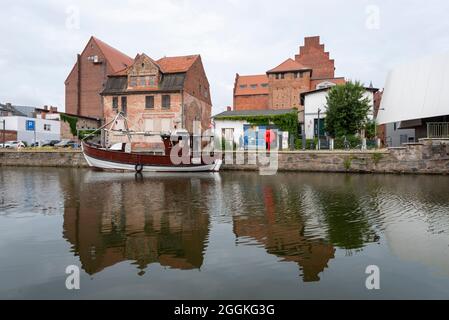 Allemagne, Mecklembourg-Poméranie occidentale, Stralsund, un bateau de pêche est ancré dans le port de la ville, derrière lui de vieux bâtiments de stockage peuvent être vus Banque D'Images