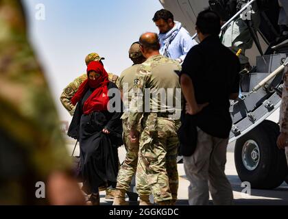 Les évacués afghans quittent un Globemaster C-17 américain après leur arrivée à la base aérienne Ali Al Salem, au Koweït, le 26 août 2021. Le ministère de la Défense s'est engagé à appuyer l'évacuation des citoyens américains, des demandeurs de visa d'immigrant spécial et d'autres personnes à risque en provenance d'Afghanistan. (É.-U. Photo de la Force aérienne par le sergent d'état-major. Ryan Brooks) Banque D'Images