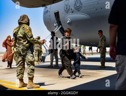 Les évacués afghans quittent un Globemaster C-17 américain après leur arrivée à la base aérienne Ali Al Salem, au Koweït, le 26 août 2021. Le ministère de la Défense s'est engagé à appuyer l'évacuation des citoyens américains, des demandeurs de visa d'immigrant spécial et d'autres personnes à risque en provenance d'Afghanistan. (É.-U. Photo de la Force aérienne par le sergent d'état-major. Ryan Brooks) Banque D'Images