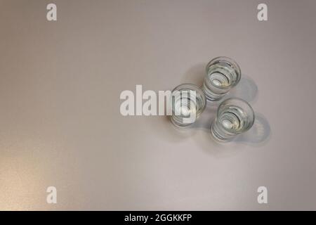Trois coups de tequila, petits coups de tequila sur fond blanc. Tableau blanc en arrière-plan. Banque D'Images