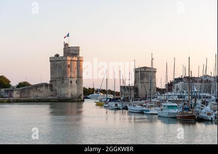 La Rochelle, France ; 10 août 2021 : entrée de l'ancien port médiéval de la Rochelle au crépuscule. Flanquée de la Tour de Saint Nicolas sur la gauche de Banque D'Images