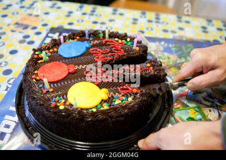 Homme coupant gâteau d'anniversaire au chocolat, gros plan - USA Banque D'Images