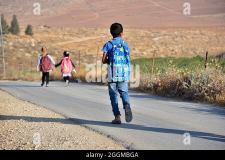 Depuis 2004, les enfants du village de Tuba se mettent à l'école dans le village voisin d'AT-Tuwani, A 2.6 km - tout en étant chaperé par un militant juif et un véhicule des forces de défense israéliennes afin des protéger des attaques violentes des colons juifs religieux contre l'avant-poste illégal de Maon Farm qui se trouve sur leur chemin vers l'école. Palestine / Israël, au sud d'Hébron. 31 août 2021. (Photo par Matan Golan/Alay Live News) Banque D'Images