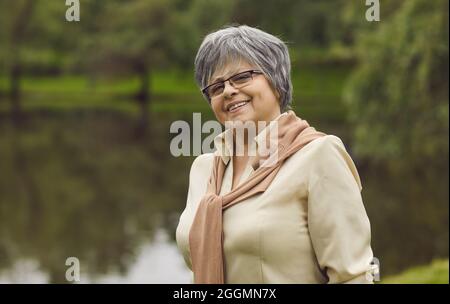 Portrait extérieur d'une femme âgée heureuse sur fond de verdure du parc d'été Banque D'Images