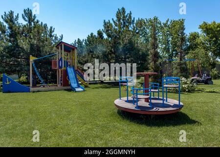 Complexe de jeux en forme de bateau pour enfants avec toboggan et carrousel sur pelouse verte en été Banque D'Images