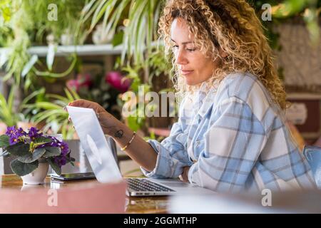 Travailleur à distance freelance femme adulte en activité de travail intelligente assis à la table à la maison ou en activité de magasin de collègue - emploi moderne en ligne et Banque D'Images