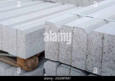 Gros plan des bordures grises empilées sur des palettes. Nouvelles bordures en béton collées ensemble. Travaux de réparation et de construction. Extérieur. Mise au point sélective. Personne. Banque D'Images