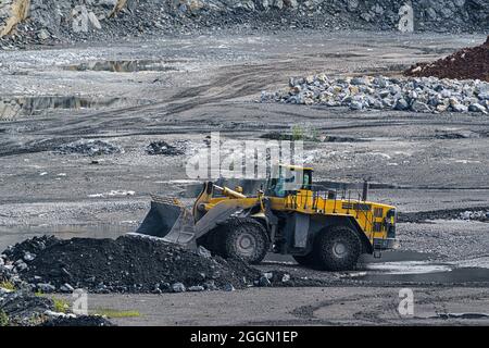 Chargeur frontal avec grandes roues et chaînes en acier. Carrière d'exploitation minière en ouvert avec machines et équipements d'exploitation minière. Extraction de calcaire pour la production de ciment. Banque D'Images