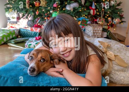 Une fille de huit ans et son chien se dressant devant l'arbre de Noël Banque D'Images