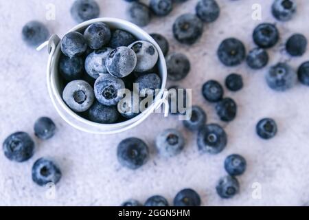 Bleuets congelés dans un petit seau sur fond de béton. Fond sain de fruits de saison biologiques. Aliments biologiques. Récolte, préparation de la nourriture Banque D'Images