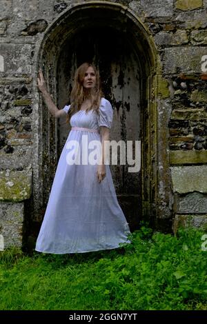 femme translucide fantôme en blanc hantant la vieille porte de l'église Banque D'Images