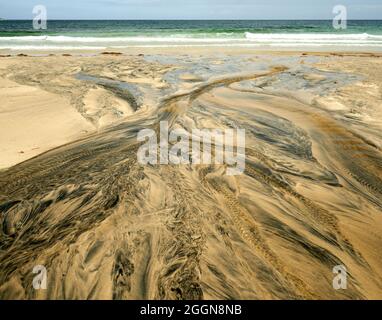 Détails fluviaux sur une plage où la tourbe est lavée dans le sable et la marée crée de beaux motifs. Reef Beach dans l'île de Lewis. Banque D'Images