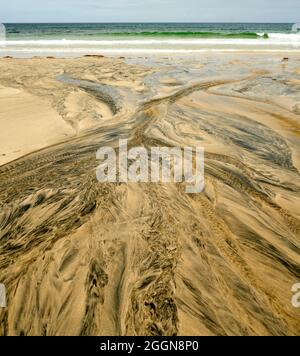 Détails fluviaux sur une plage où la tourbe est lavée dans le sable et la marée crée de beaux motifs. Reef Beach dans l'île de Lewis. Banque D'Images