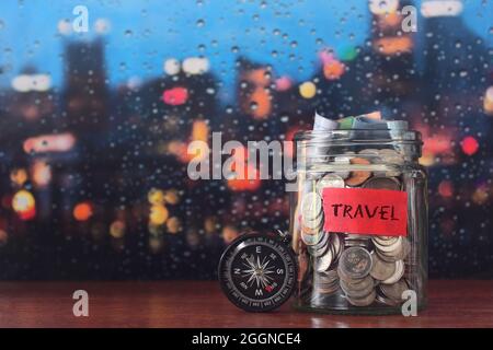 Concept de budget de voyage. Faites des économies dans un pot en verre avec boussole. Copier l'espace pour le texte Banque D'Images