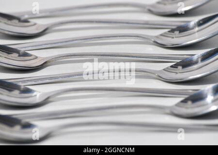 Cuillères à soupe en acier inoxydable disposées sur un fond blanc selon un schéma répétitif Banque D'Images