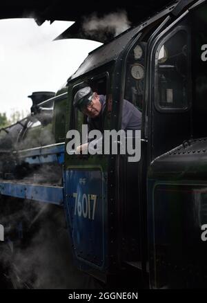 Un chauffeur de train descendant la plate-forme de la gare pendant un arrêt à la gare d'Alresford sur la ligne Watercress, Alresford, Hampshire, Royaume-Uni. Banque D'Images