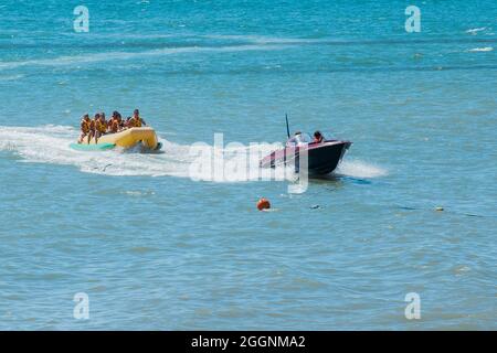 Ukraine, Port de fer - 24 août 2020 : les hommes sur un bateau à moteur et dispersent les vacanciers et les touristes sur une banane gonflable sur la mer. Banque D'Images