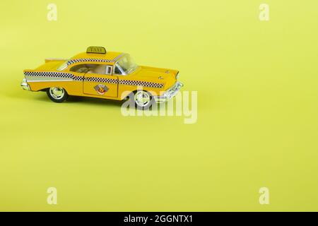 Une voiture de taxi jaune sur fond jaune pastel. Service de taxi. Banque D'Images