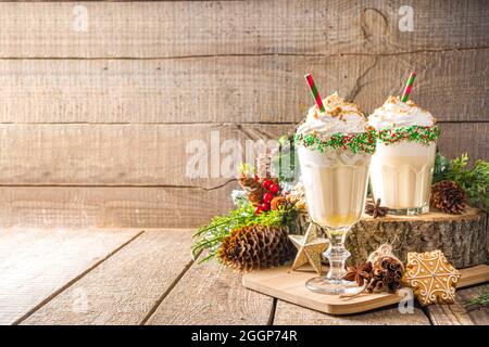 Boisson de Noël festive, cocktail de Milkshake Eggnog avec crème glacée, crème fouettée, saupoudrés de sucre colorés, sur fond traditionnel en bois avec Noël Banque D'Images