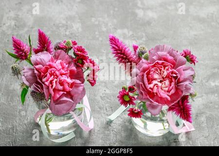 Petits bouquets avec des fleurs de carnation rose, de chrysanthème et de celosia sur fond de pierre grise, espace de copie. Banque D'Images