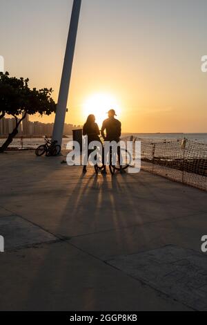 Jeune couple cycliste appréciant le coucher du soleil à Fortaleza Ceara Brésil Banque D'Images