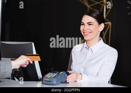 un réceptionniste souriant près d'un client payant avec une carte de crédit Banque D'Images